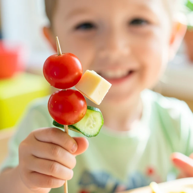 Child excitedly holding a fun vegetable skewer to try new tastes